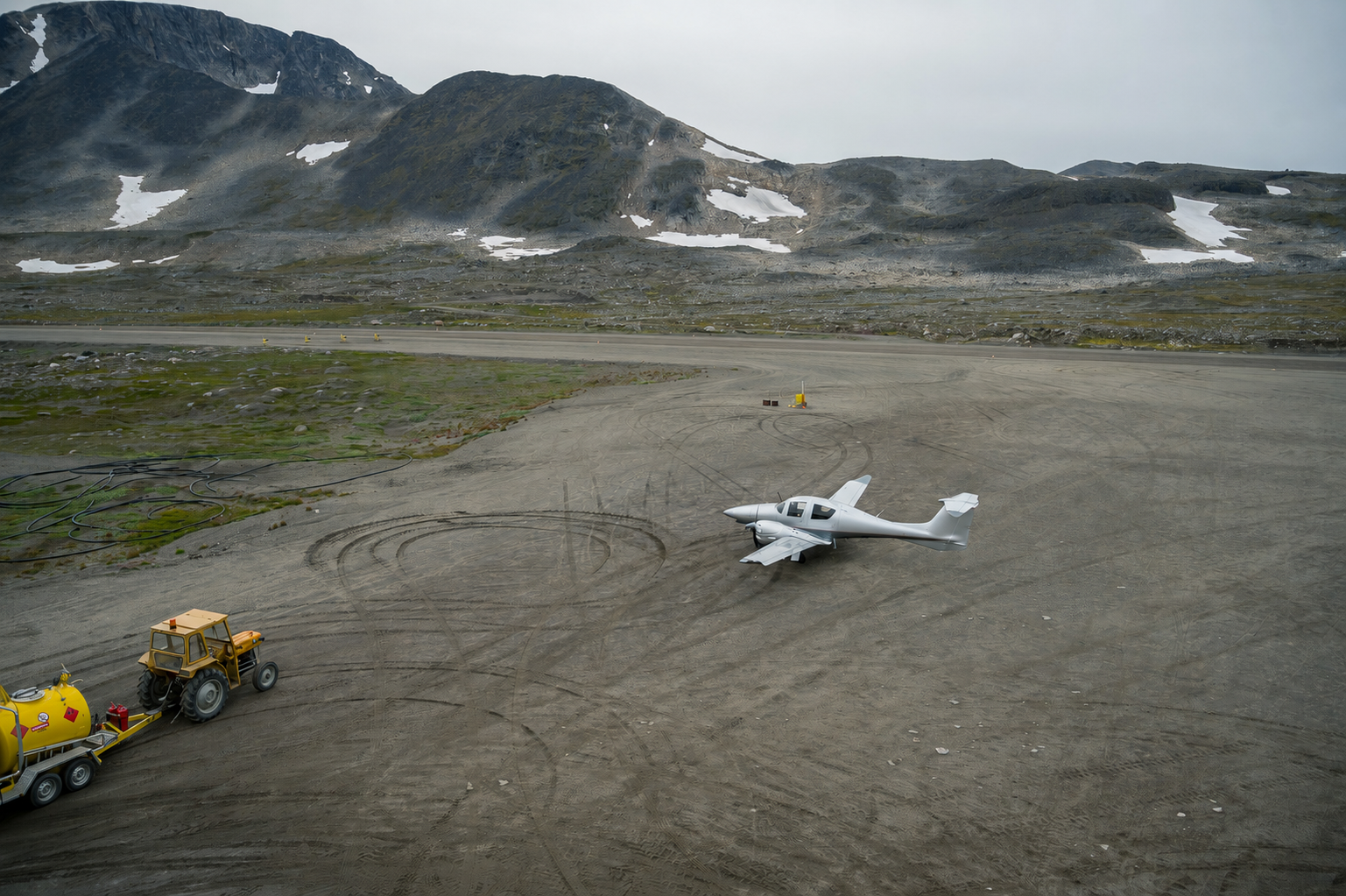 A Diamond aircraft on a remote Greenland apron beside local fuel handling equipment