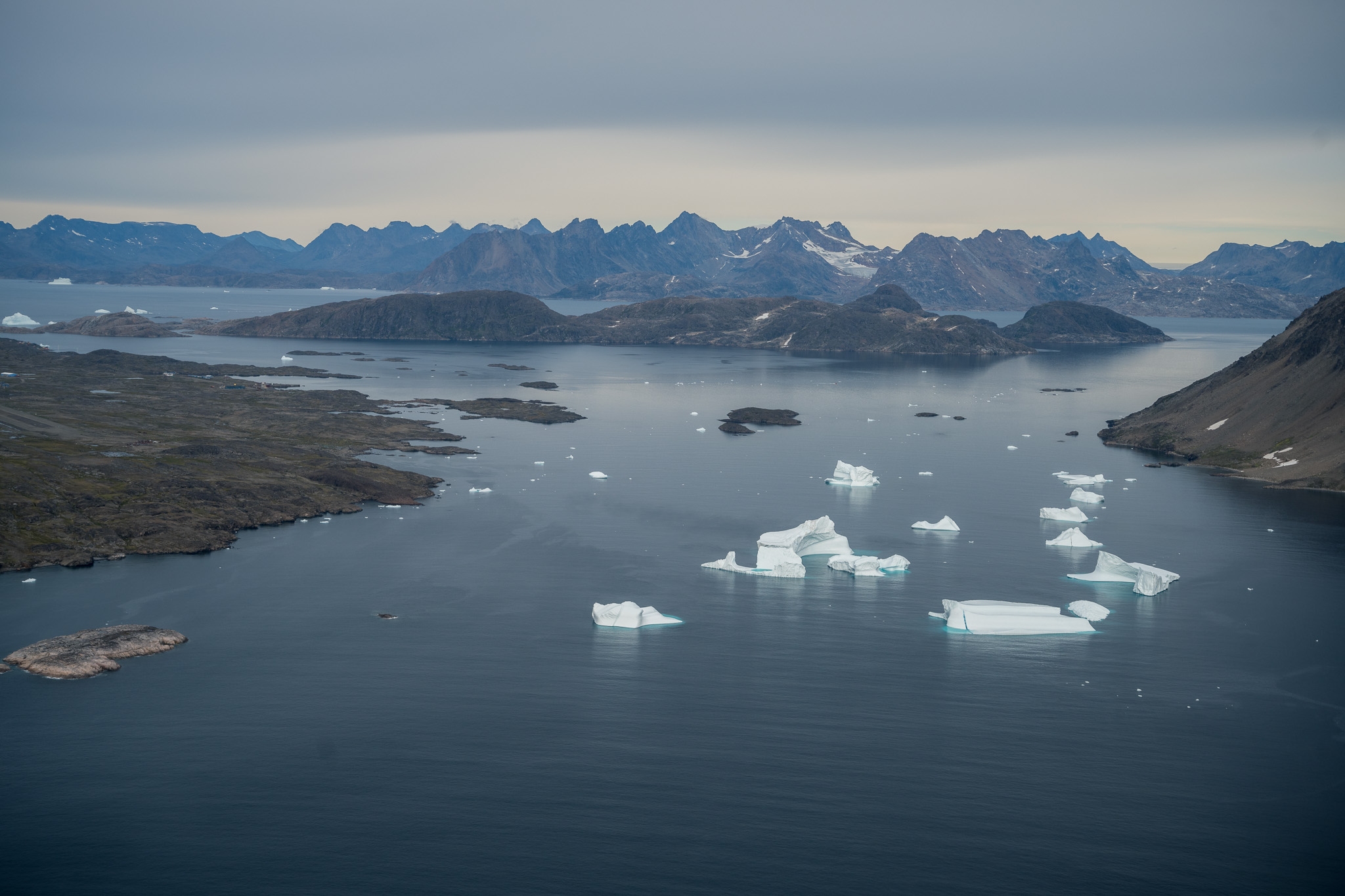 Icebergs floating between mountain ranges in a Greenland fjord